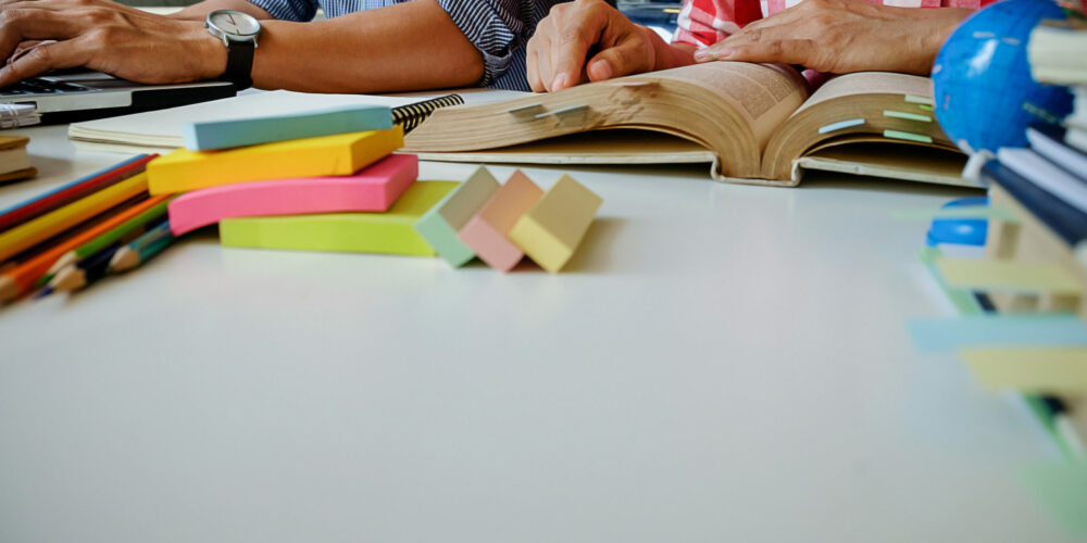 Education concept. Students studying and brainstorming campus concept. Close up of students discussing their subject on books  textbooks and writing to notebook. Seclective focus.